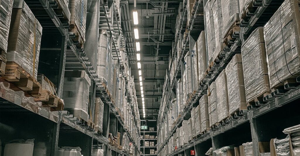 A long aisle in a modern warehouse with high shelving filled with boxes and supplies.